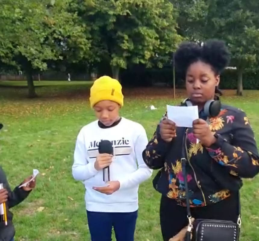 Two young people rapping outdoors with a microphone